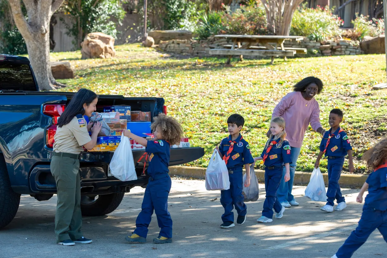 Cub Scouts carrying donated groceries to a pickup truck during Scouting for Food